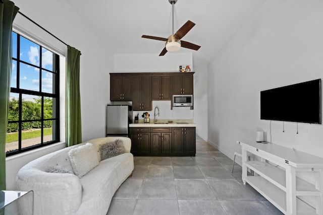 interior space with baseboards, ceiling fan, light tile patterned flooring, and vaulted ceiling