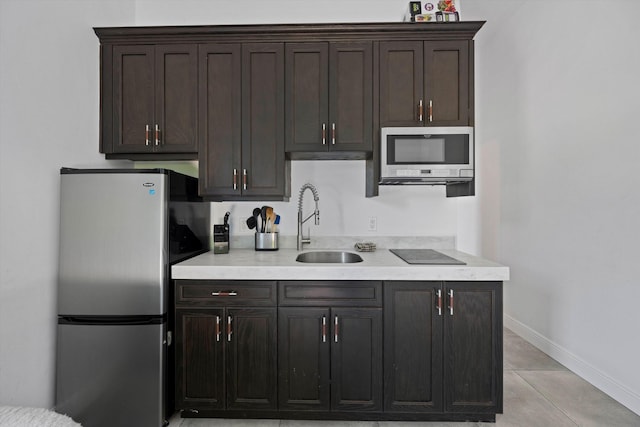 kitchen with a sink, stainless steel appliances, light countertops, baseboards, and dark brown cabinets