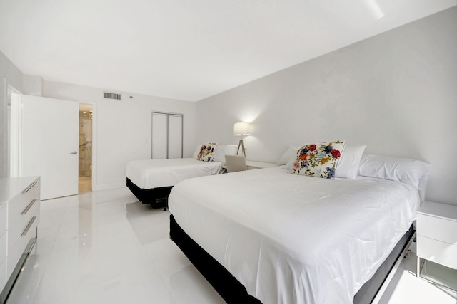 bedroom featuring light tile patterned floors, visible vents, and ensuite bathroom