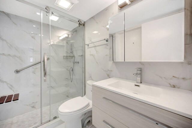 full bath with a marble finish shower, toilet, tile walls, and vanity