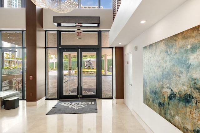 entryway with french doors, baseboards, a towering ceiling, and expansive windows