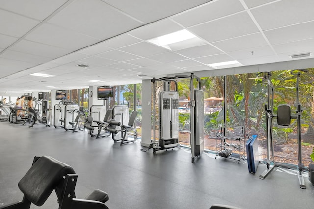 workout area with a drop ceiling, floor to ceiling windows, and visible vents