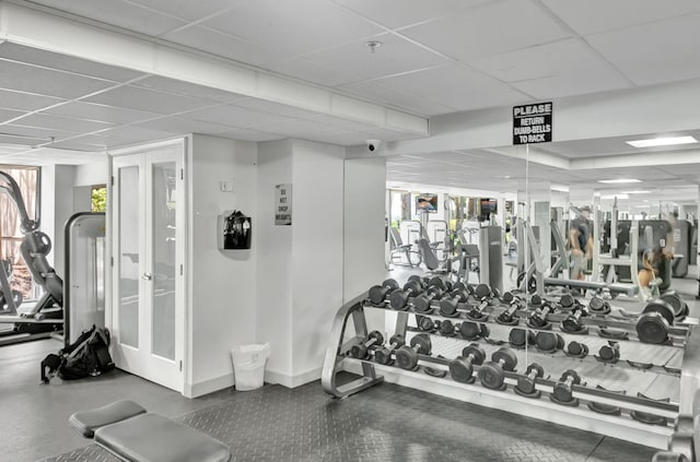 workout area featuring a paneled ceiling and baseboards