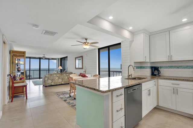 kitchen featuring visible vents, a sink, stainless steel dishwasher, floor to ceiling windows, and a peninsula