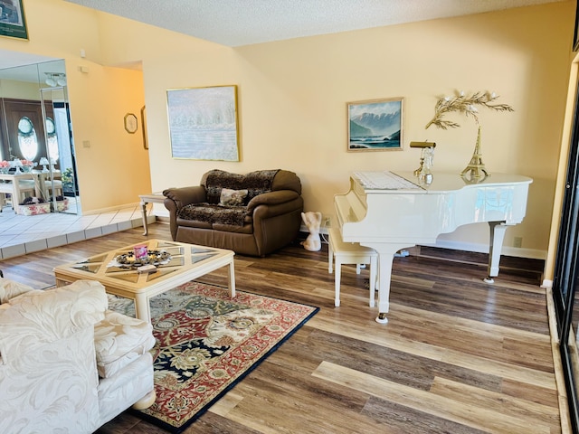 living room with a textured ceiling, wood finished floors, and baseboards