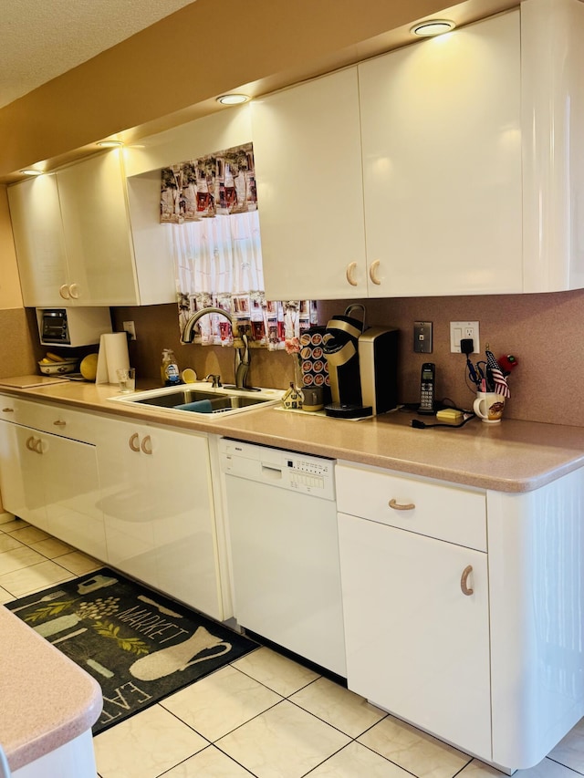 kitchen with light countertops, dishwasher, white cabinetry, and a sink
