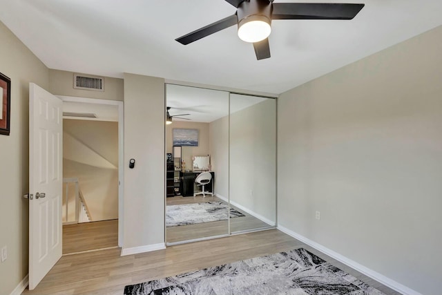 unfurnished bedroom with a closet, visible vents, a ceiling fan, and wood finished floors