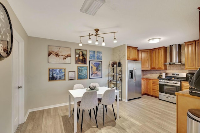 kitchen with decorative backsplash, light wood finished floors, wall chimney exhaust hood, and appliances with stainless steel finishes