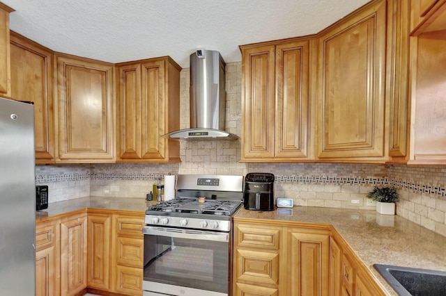 kitchen with light countertops, wall chimney range hood, backsplash, and appliances with stainless steel finishes