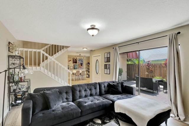 living room featuring a chandelier, a textured ceiling, wood finished floors, and stairs