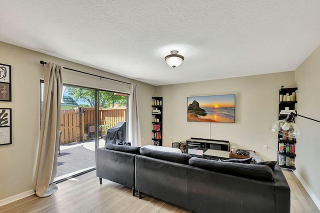 living room with light wood-style floors, baseboards, and a textured ceiling