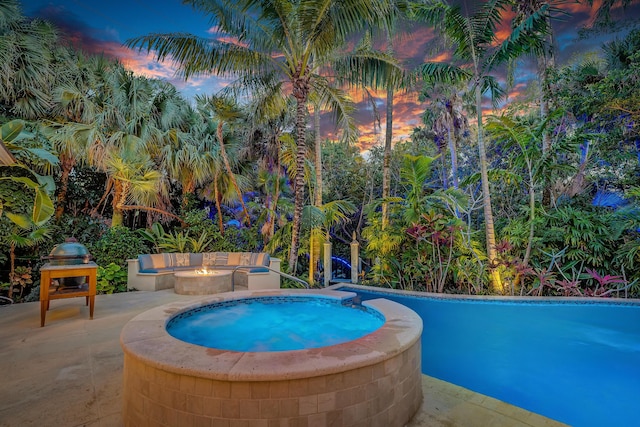 pool at dusk with a patio and a fire pit