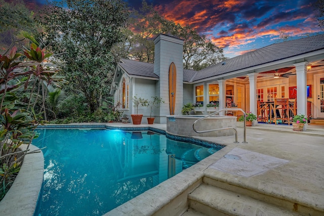 pool at dusk with an outdoor pool and a patio area