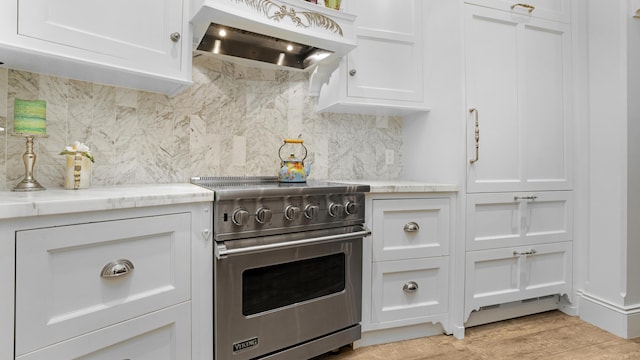 kitchen featuring premium range hood, white cabinets, light wood-style floors, premium range, and tasteful backsplash