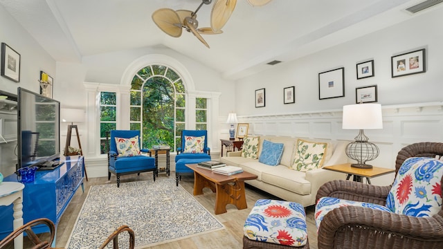 living area with lofted ceiling, wood finished floors, visible vents, and wainscoting