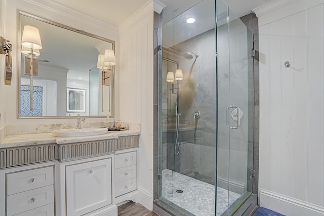 bathroom featuring vanity, a shower stall, and crown molding