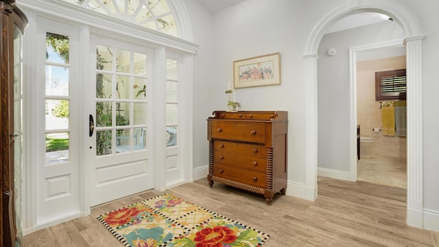 entryway featuring light wood-style floors, arched walkways, and baseboards