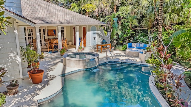 view of swimming pool featuring a patio area, a pool with connected hot tub, and an outdoor fire pit