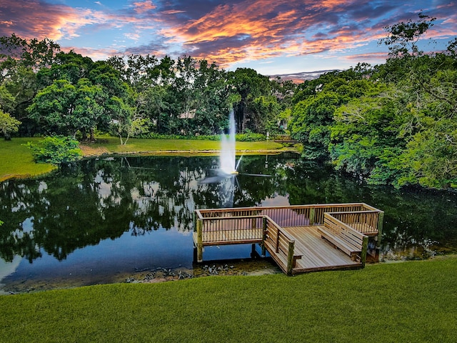 view of dock with a lawn and a water view