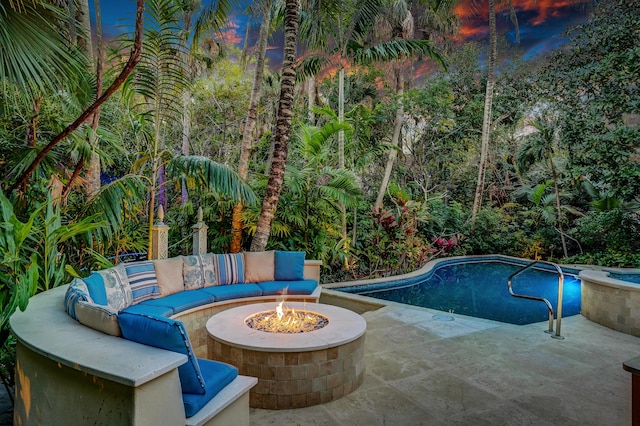 pool with an outdoor living space with a fire pit and a patio