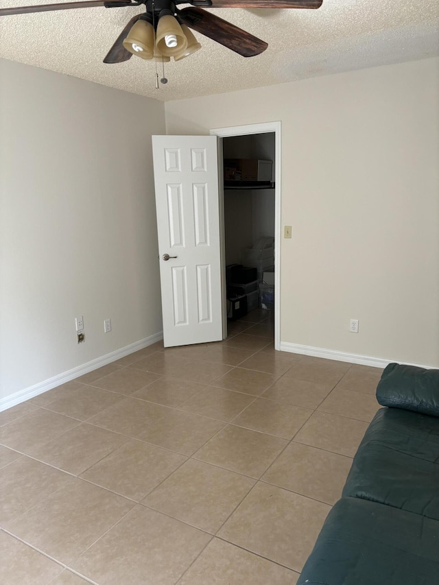 interior space with light tile patterned flooring, baseboards, a textured ceiling, and ceiling fan