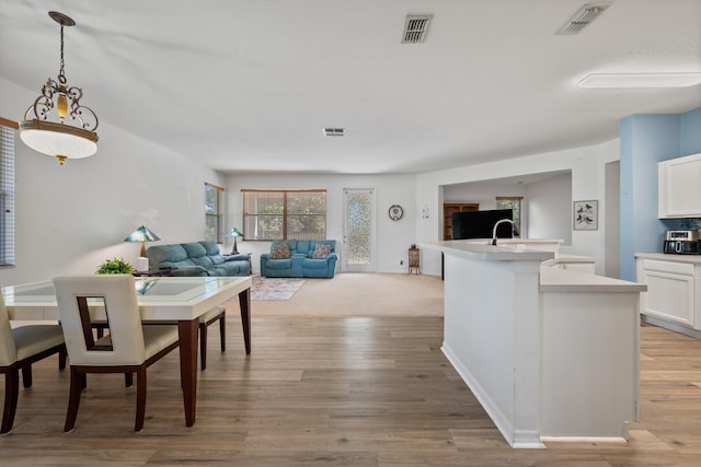 kitchen with visible vents, an island with sink, and white cabinets