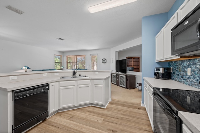 kitchen featuring visible vents, a sink, black appliances, light countertops, and light wood-style floors