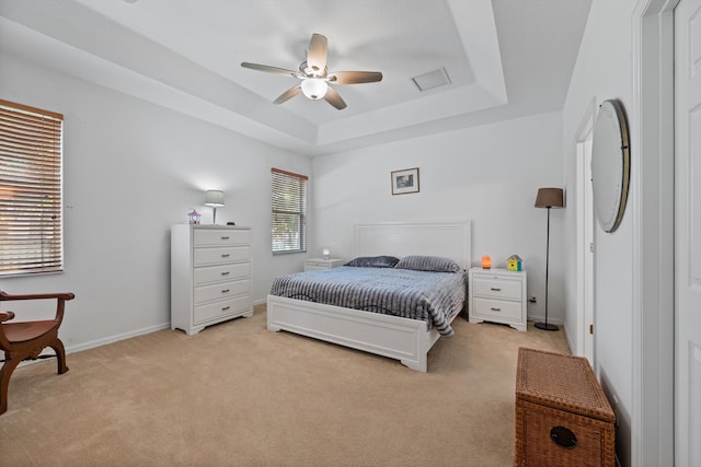 bedroom featuring visible vents, light carpet, a raised ceiling, a ceiling fan, and baseboards