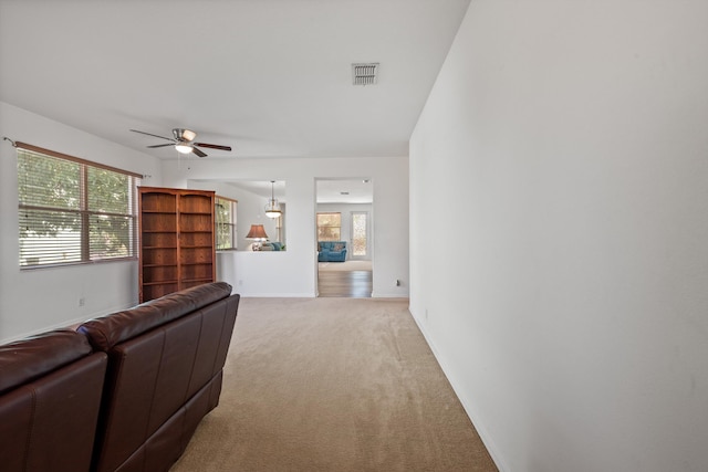 carpeted living area with baseboards, visible vents, and ceiling fan