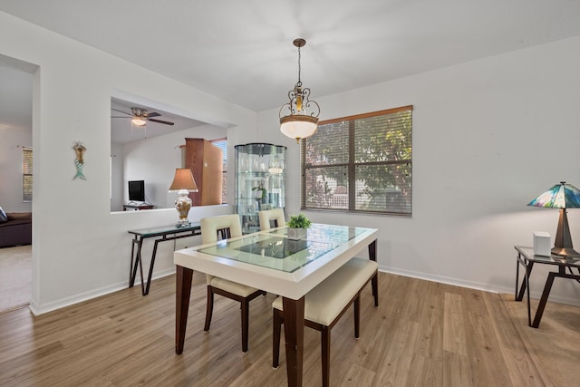 dining area featuring baseboards, ceiling fan, and light wood finished floors