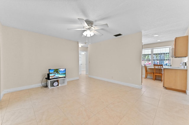 living area featuring a textured ceiling, baseboards, visible vents, and ceiling fan