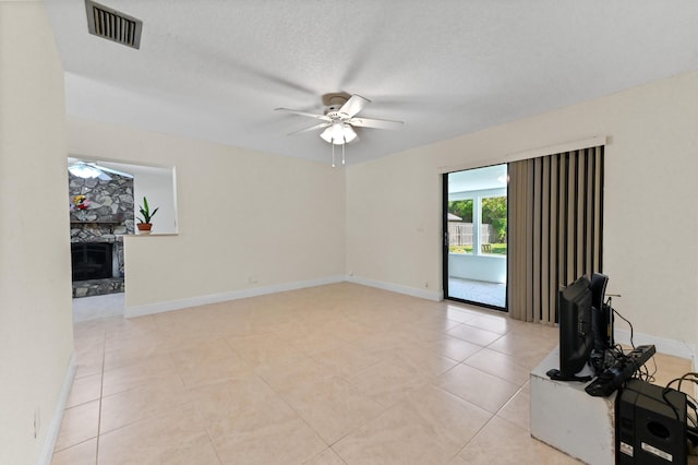 unfurnished living room with baseboards, a fireplace, visible vents, and ceiling fan