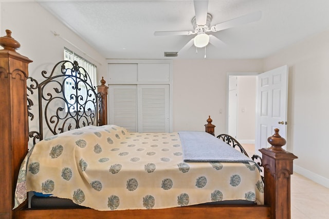 bedroom featuring a ceiling fan, visible vents, baseboards, light tile patterned flooring, and a closet