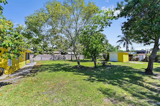 view of yard with an outbuilding, a storage unit, and fence