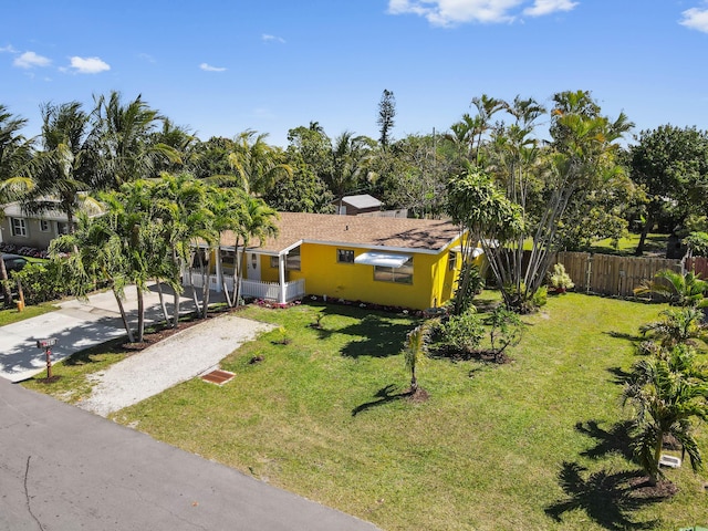 view of front facade with stucco siding, a front lawn, driveway, and fence