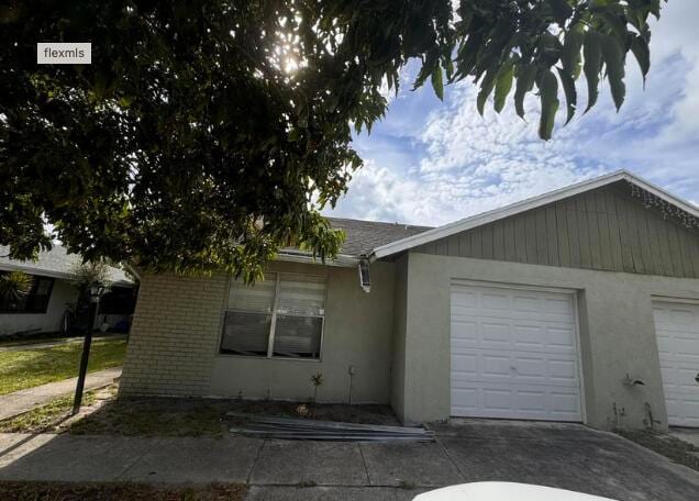 view of front facade featuring brick siding, stucco siding, concrete driveway, and a garage