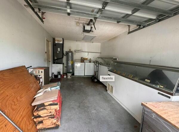 garage featuring heating unit, a garage door opener, independent washer and dryer, and water heater