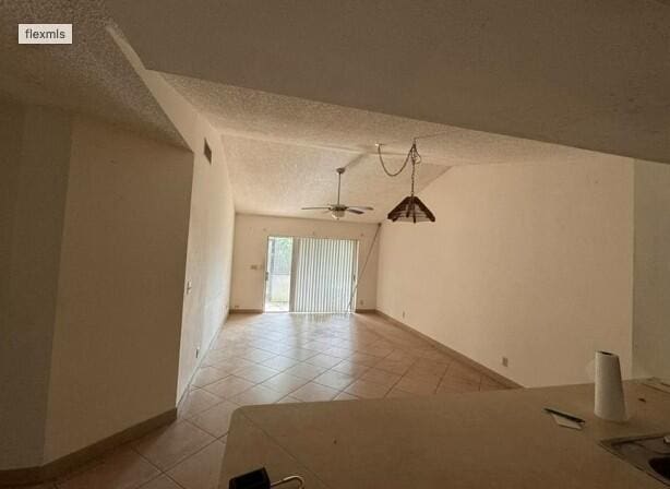 unfurnished room featuring visible vents, a ceiling fan, a textured ceiling, light tile patterned floors, and lofted ceiling