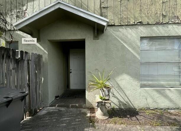 entrance to property with fence and stucco siding