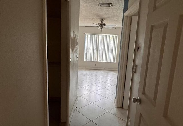 hallway with light tile patterned floors, visible vents, and a textured ceiling