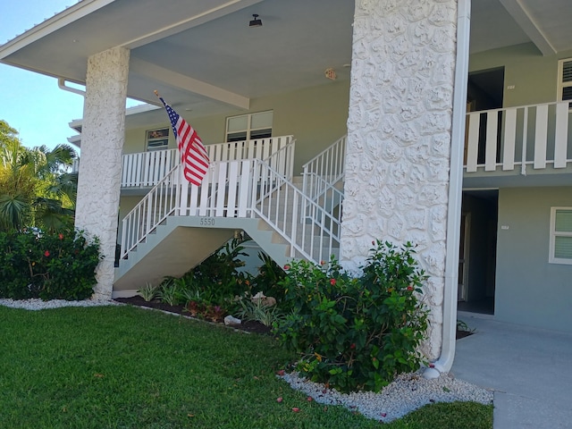 view of home's exterior featuring stucco siding, a yard, and stairs