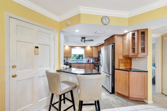 kitchen featuring glass insert cabinets, a breakfast bar area, ornamental molding, decorative backsplash, and freestanding refrigerator