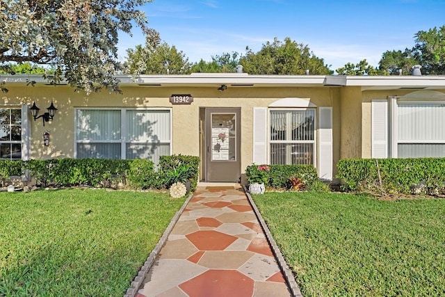 property entrance with stucco siding and a yard