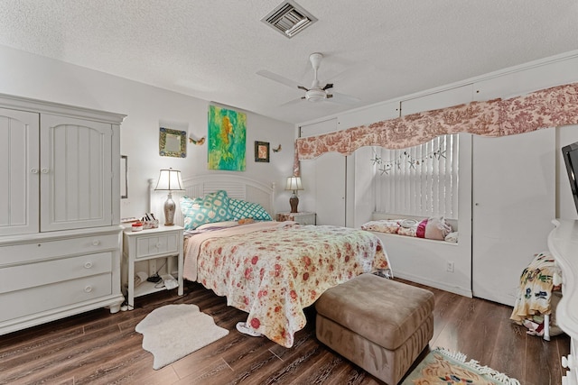 bedroom with ceiling fan, visible vents, dark wood-style flooring, and a textured ceiling