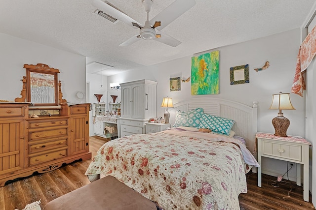 bedroom with wood finished floors, visible vents, attic access, ceiling fan, and a textured ceiling