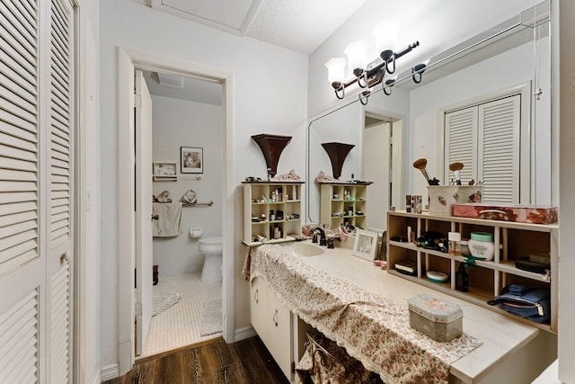 bathroom featuring baseboards, toilet, wood finished floors, a closet, and vanity