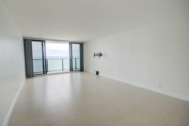 unfurnished room with baseboards and expansive windows