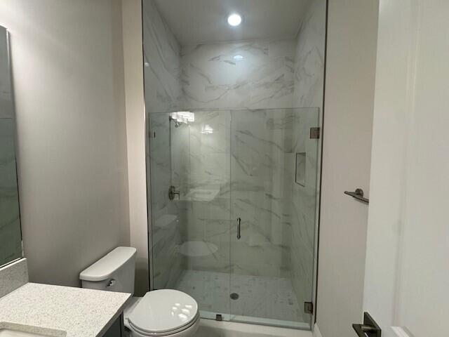 full bath featuring vanity, toilet, and a marble finish shower