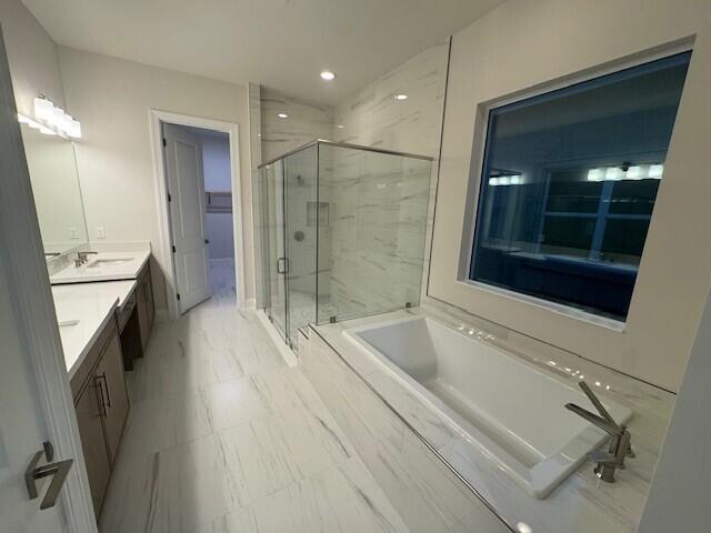 bathroom featuring a garden tub, a sink, recessed lighting, a marble finish shower, and double vanity