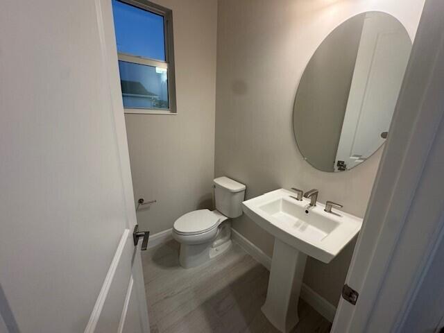 bathroom with toilet, baseboards, and a sink